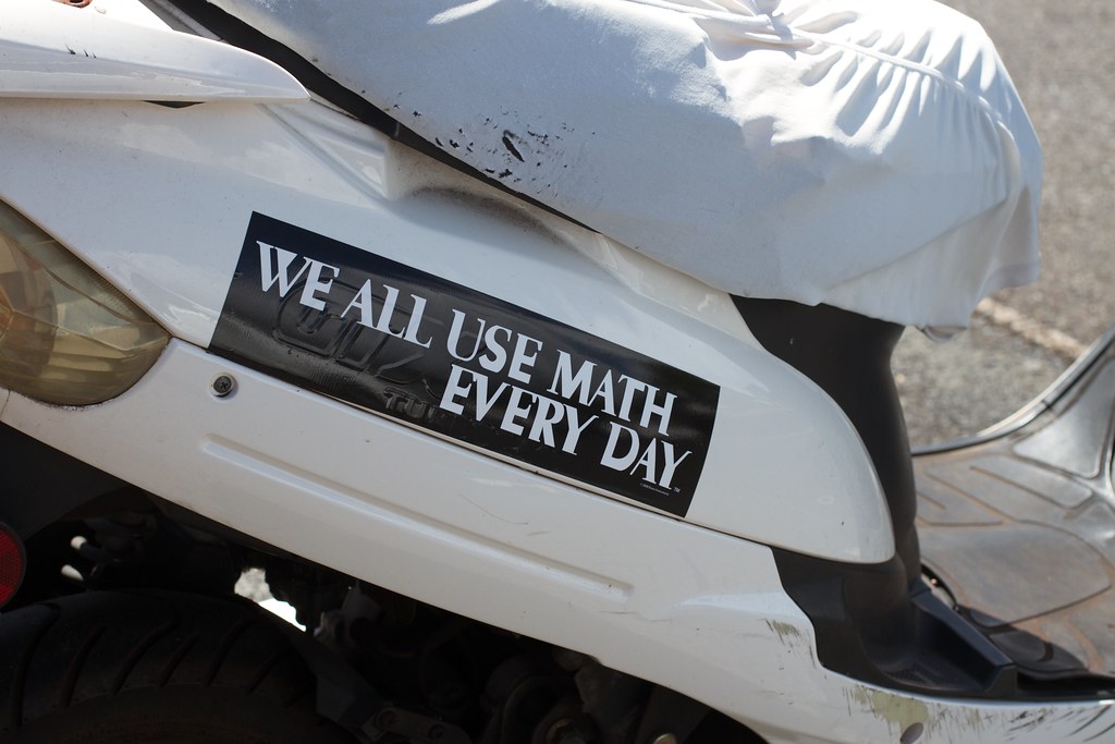 A white car with a bumper sticker that says "We all use math every day"