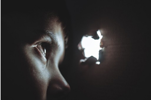 A person looking through a hole in a wall