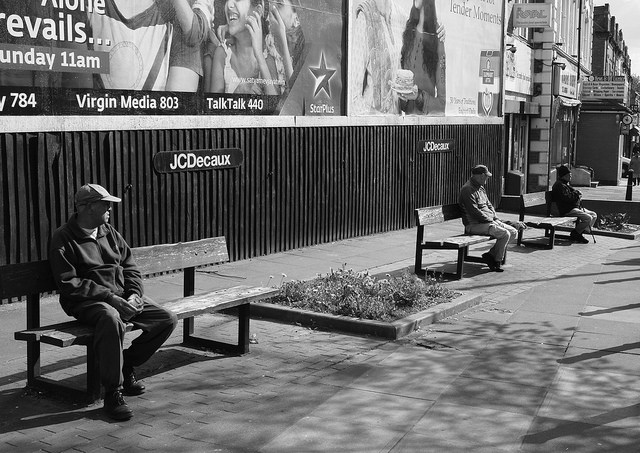 People sitting on benches distanced from each other.