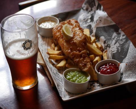 Glass of beer with a plate of food.