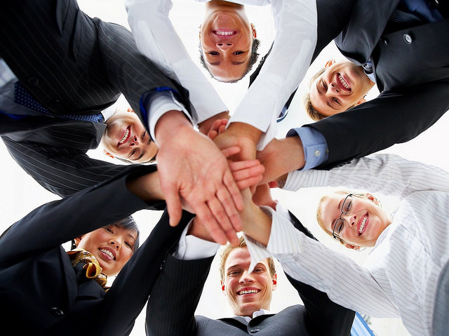 A team smiling with all their hands together in a circle