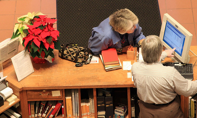 A customer service representative showing a customer something on a computer.