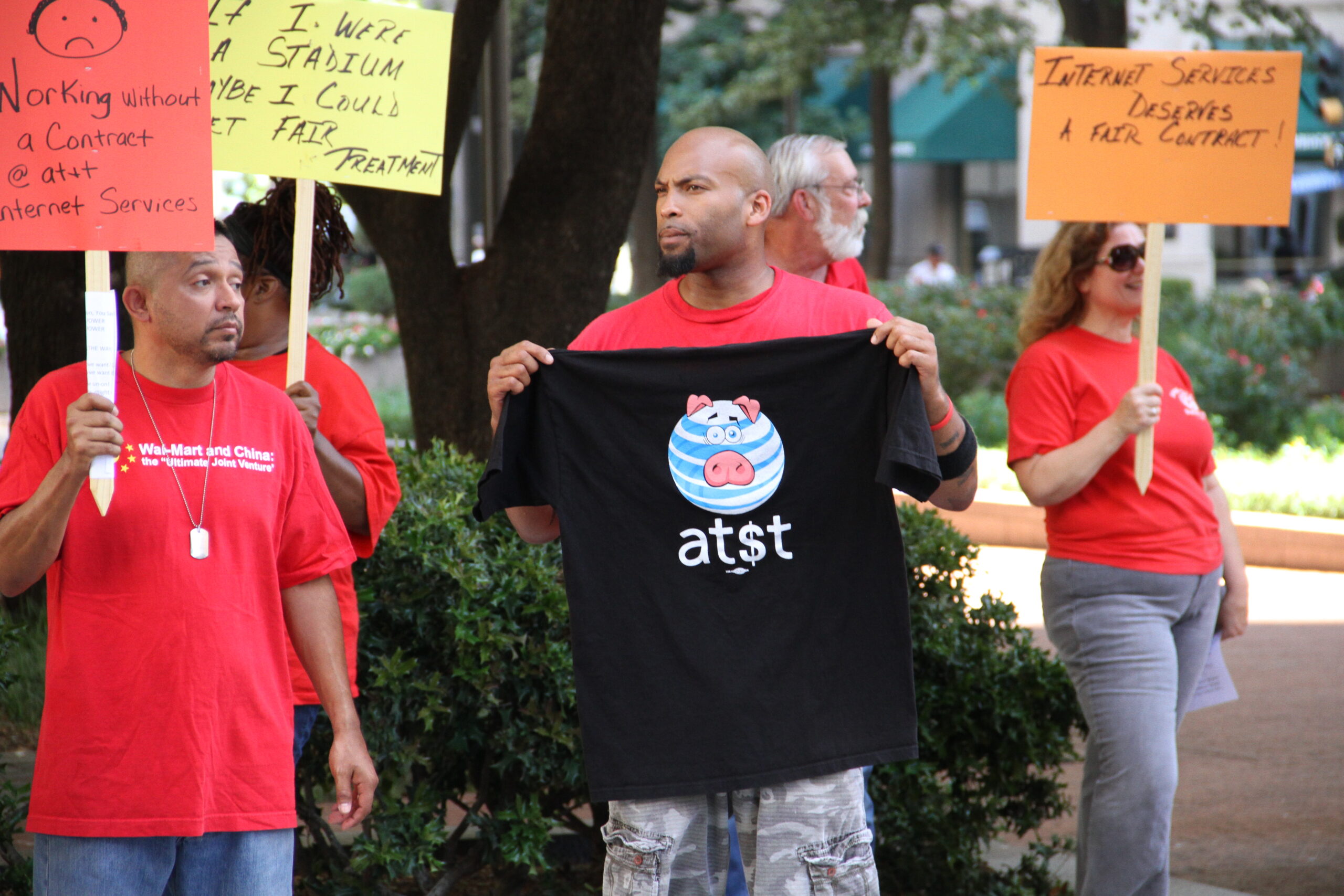 Workers holding up signs and t-shirts advocating for a fair contract.