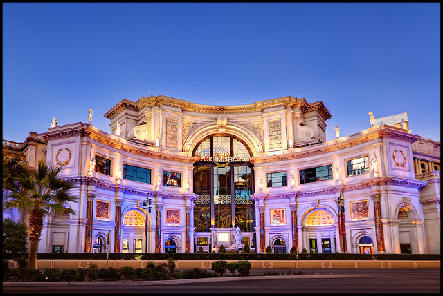 A view of the Caesar's Palace Forum Shops just after sunrise. Sunrise and night are very different in Las Vegas, as one would expect. There's nobody on the street at sunrise, except for a few people who are just calling it a night. The building is beautifully lit with purple light.