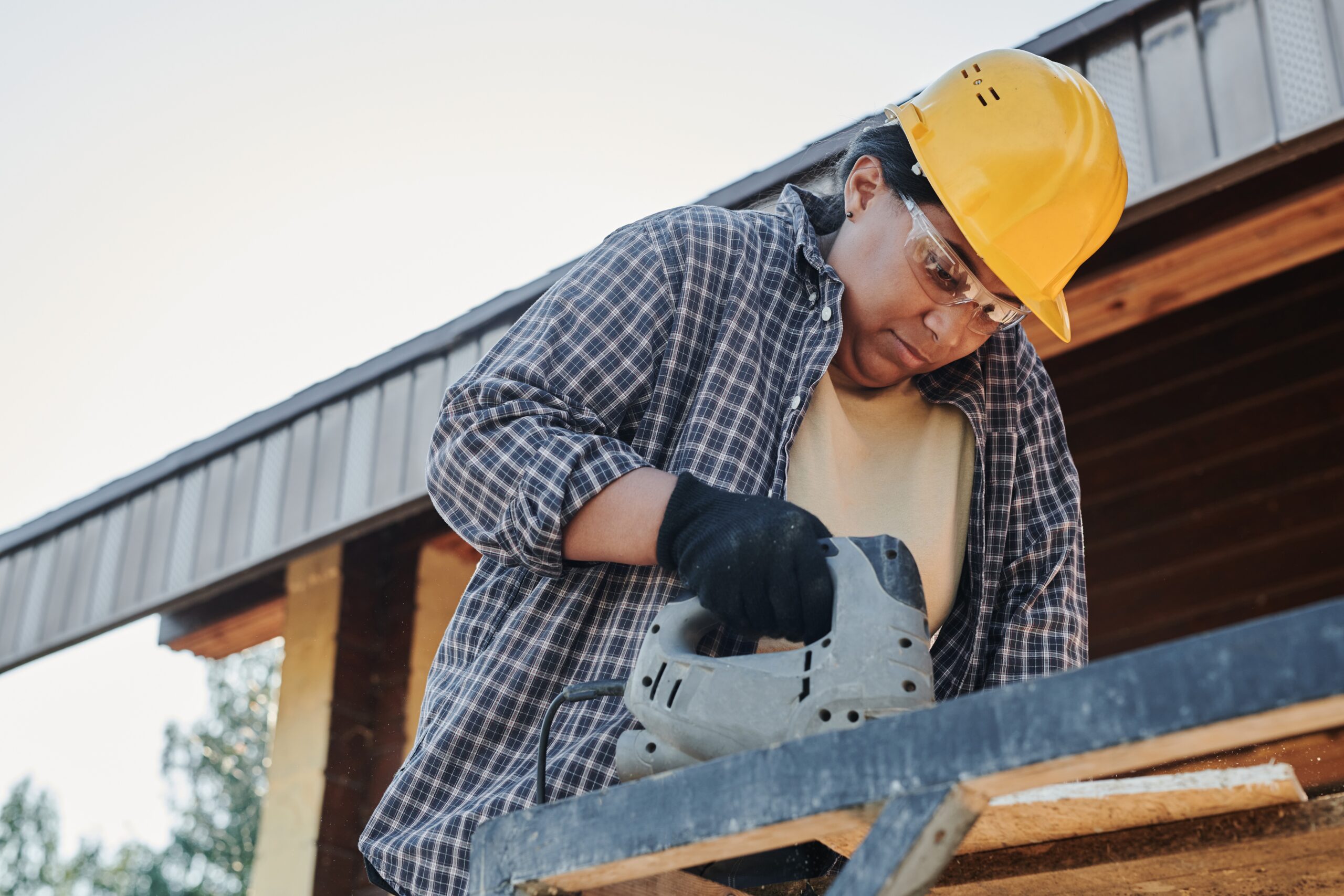 A woman wearing a hard hat and safety goggles working at a construction site.