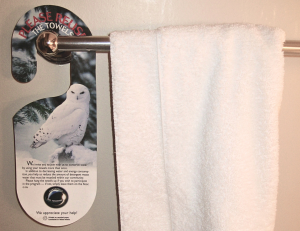 Towel rack with a social norm and environmental message requesting guests to reuse towels