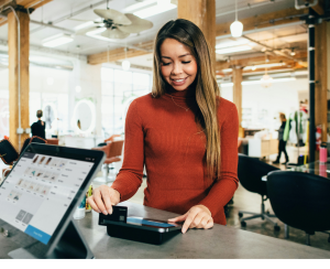 A woman in a red turtleneck swiping her credit card